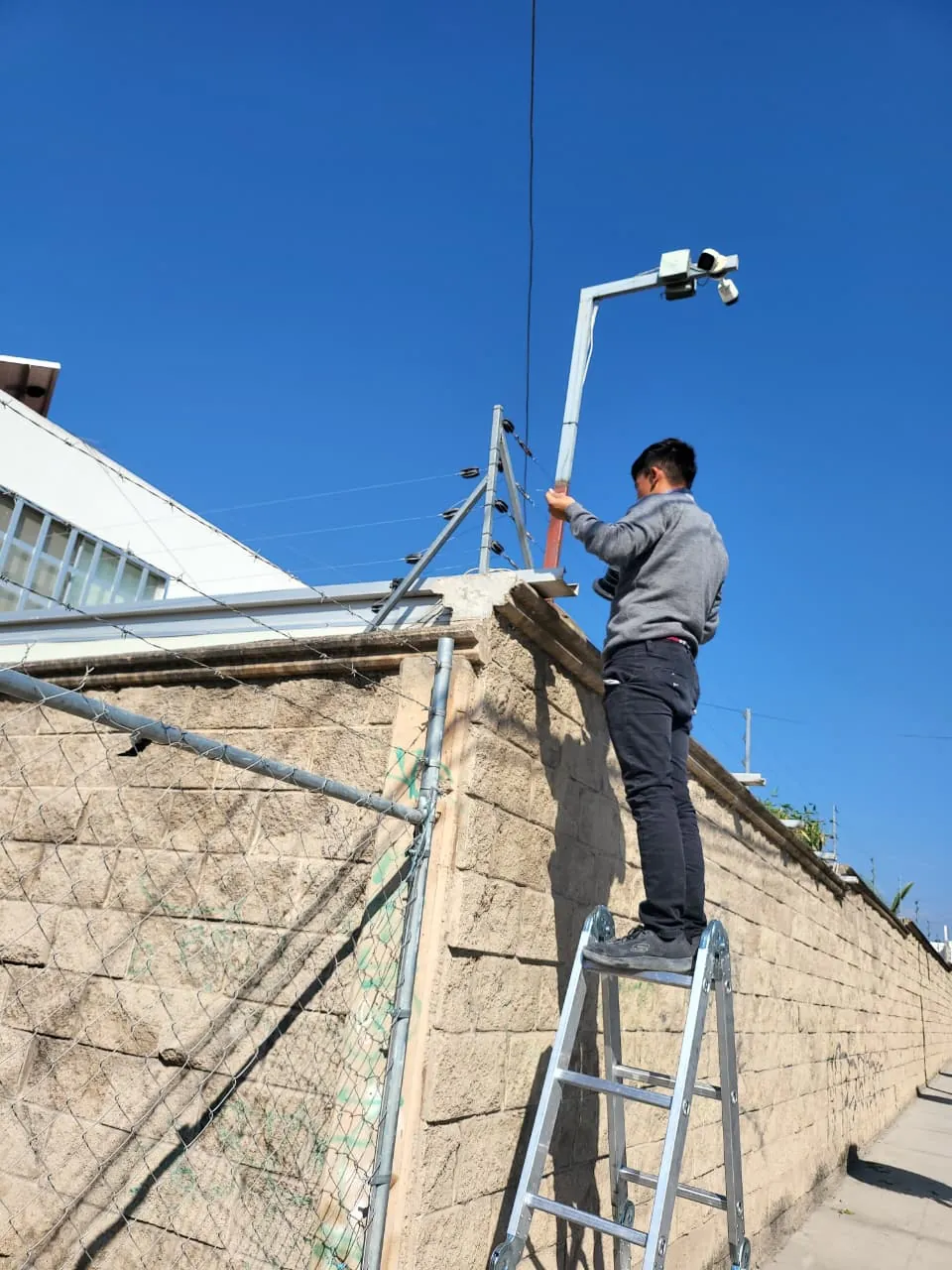 Técnico instalando una cámara de seguridad junto a un acceso